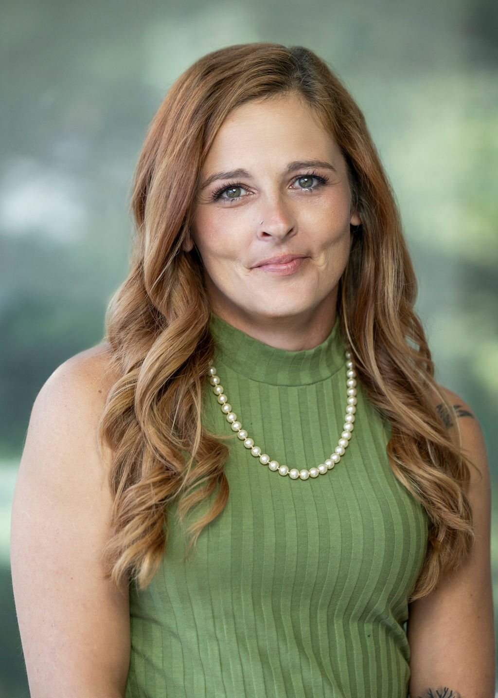 Woman with long red hair and a light green tank top against a green background