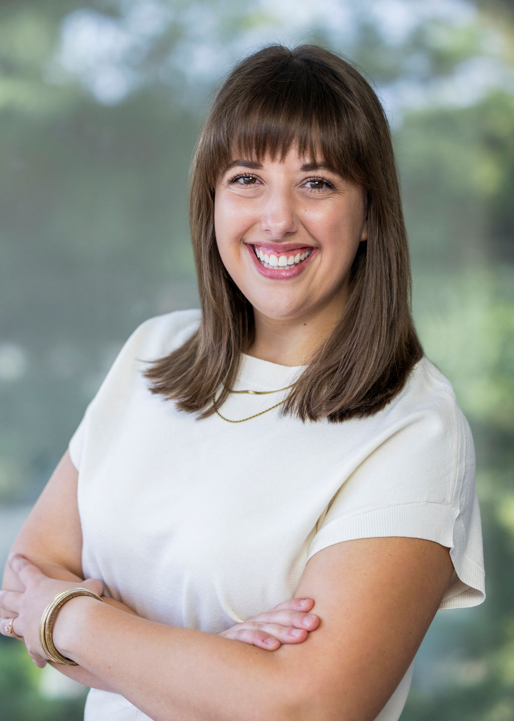 Woman in a white t-shirt with brown hair against a green background